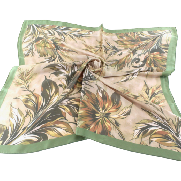 Cream square scarf with a flowing botanical print in green, ochre, and warm neutrals, framed by a green border.