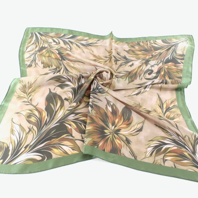 meredith Cream square scarf with a flowing botanical print in green, ochre,  neutrals, framed by a green border.