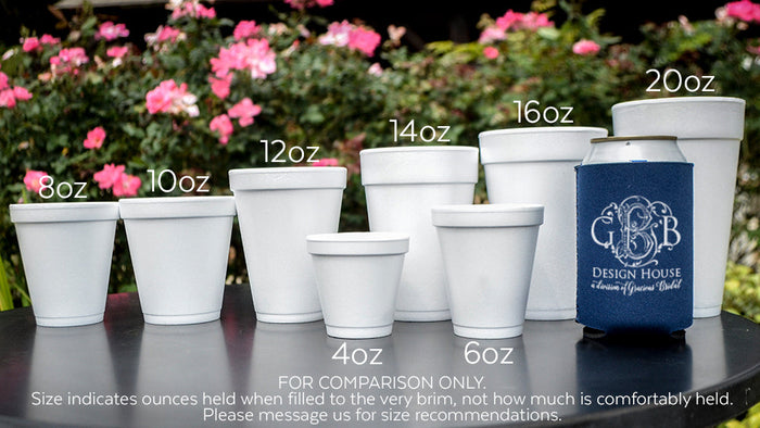 A collection of white foam cups and a blue cup sleeve on a table, with pink flowers in the background.