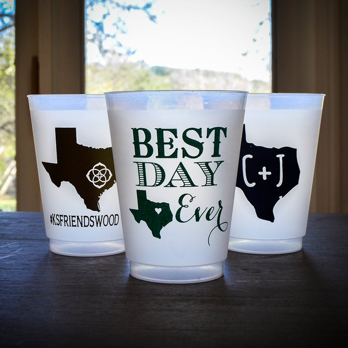 Three white plastic cups with black designs and text on them, placed on a wooden surface.