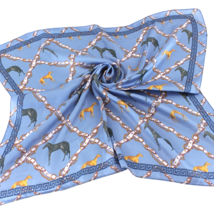 Blue square scarf featuring dark horses, golden hounds, and a rope-like lattice pattern in warm neutral tones.