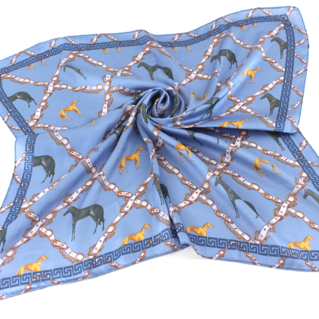 Blue square scarf featuring dark horses, golden hounds, and a rope-like lattice pattern in warm neutral tones.