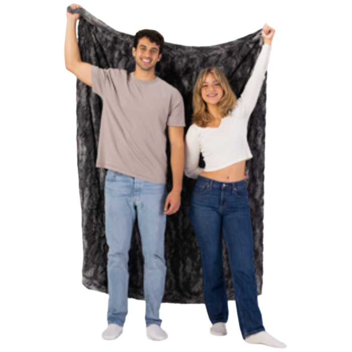 Two people holding up a large black and gray patterned blanket against a white background