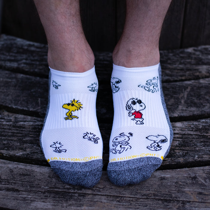 White and black marled quarter compression socks for men with Snoopy designs, worn in a lifestyle setting.