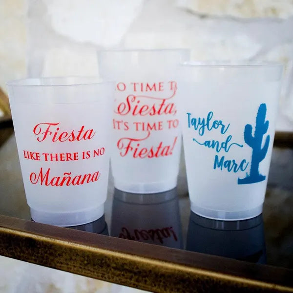 Three plastic cups with text printed on them, placed on a reflective surface.