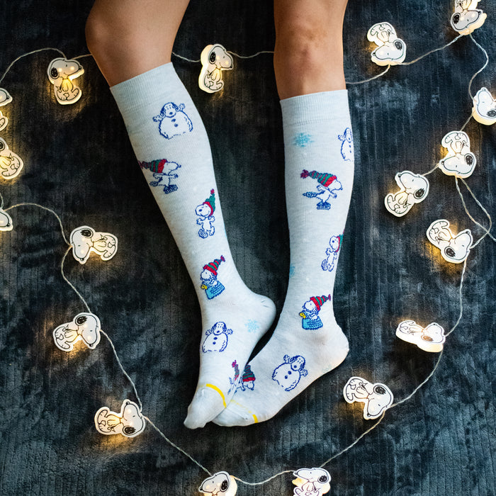 Pale blue heather knee-high compression socks with Snoopy winter designs, worn in a lifestyle setting.